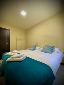 1 dormitorio con 2 camas grandes y almohadas azules en Mi Refugio, en Arenas de San Pedro