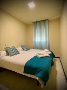 sypialnia z łóżkiem z niebieskimi poduszkami i oknem w obiekcie Mi Refugio w mieście Arenas de San Pedro