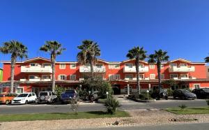 un grand bâtiment rouge avec des palmiers dans un parking dans l'établissement Zen House Morabeza, à Santa Maria