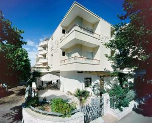 a tall white building with a fence in front of it at Hotel Albatros in Misano Adriatico