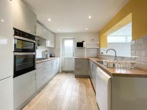 una grande cucina con armadi bianchi e lavandino di Well Situated, Cosy 2 Bed House a West Kirby