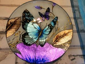 una placa de vidrio con mariposas en una placa púrpura en Casa Rural Eneida, en Chiquenge
