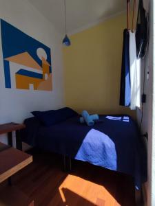 a bedroom with a blue bed with a blue stuffed animal on it at La Galería B&B in Valparaíso
