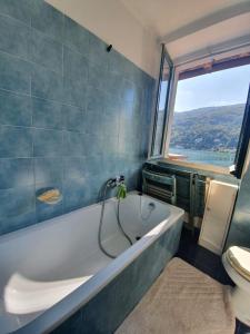 Un baño con bañera, inodoro y ventana. en La casa sul tetto, en Stresa