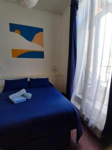Un dormitorio con una cama azul y una ventana en La Galería B&B, en Valparaíso
