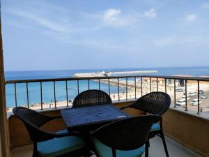 a table and chairs on a balcony overlooking the beach at Mermaid House in Alexandria