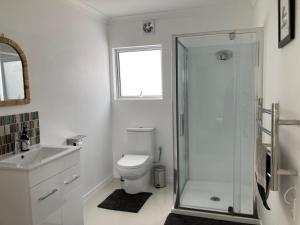 a white bathroom with a shower and a toilet at Kauri Point Village in Tahawai