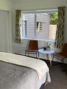 a bedroom with a bed and a table and a window at Kauri Point Village in Tahawai