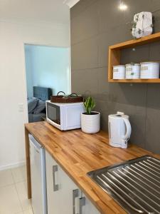 a kitchen counter with a microwave on a wooden counter top at Kauri Point Village in Tahawai