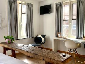 a living room with a wooden bench and windows at Hotel Au Nom De Dieu in Dilsen-Stokkem