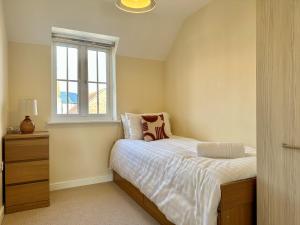 1 dormitorio con cama y ventana en Homely 3 bedroomed House in Bicester, en Bicester