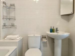 Un baño blanco con inodoro y lavabo. en Homely 3 bedroomed House in Bicester, en Bicester 11 fotos más
