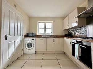 una cocina blanca con lavadora y secadora. en Homely 3 bedroomed House in Bicester, en Bicester