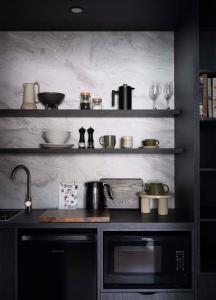 a kitchen with a sink and shelves with pots and pans at Tallowwood House Luxury Bed & Breakfast in Port Macquarie +29 photos