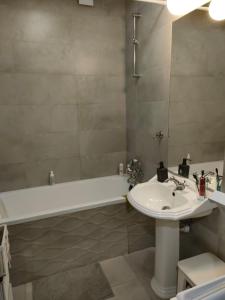 ein Badezimmer mit einem Waschbecken, einer Badewanne und einem weißen Waschbecken in der Unterkunft Helski azyl in Hel