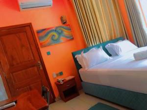 a small bedroom with a bed and a door at HÔTEL NOAHGARDEN 2 in Cotonou