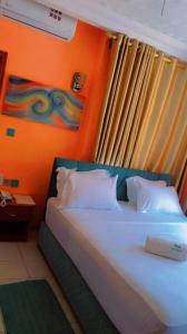 1 dormitorio con 1 cama con pared de color naranja en HÔTEL NOAHGARDEN 2, en Cotonou