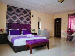 a bedroom with a large bed with purple pillows at ZUNOX GUEST HOUSE in Freetown