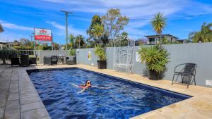 una donna che nuota in una piscina in un hotel di Chinchilla Motor Inn a Chinchilla
