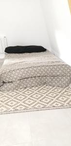 a bed with a comforter on it in a room at Equipée 1 pièce proche Paris in Argenteuil