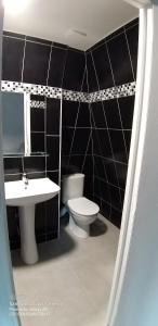 a black tiled bathroom with a toilet and a sink at Equipée 1 pièce proche Paris in Argenteuil +17 photos