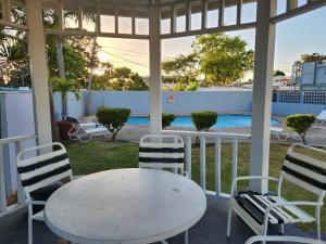 una mesa blanca y sillas en un porche con piscina en Alejandra, en San Juan