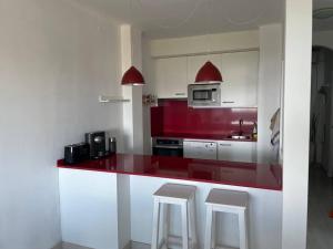 a kitchen with a red counter top and white cabinets at NUEVO. Reformado con vistas panorámicas y piscina in Pals