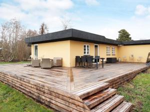 Holiday home Jægerspris XLIII في Jægerspris: سطح خشبي كبير أمام المنزل