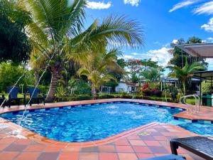 una piscina con palmeras en un patio en Finca Santa Clara, Rivera-Huila en Rivera