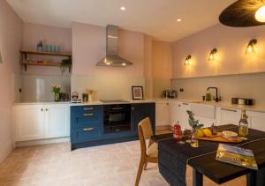 a kitchen with a table and a blue kitchen at Luxury & Location! Bakewell Georgian Townhouse - 'The Haywood' in Bakewell