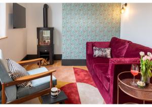 salon z fioletową kanapą i kominkiem w obiekcie Luxury & Location! Bakewell Georgian Townhouse - 'The Haywood' w mieście Bakewell