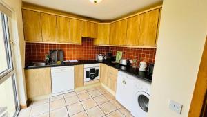 cocina con armarios de madera, lavadora y secadora en Summer Breeze - Cosy & Warm Holiday Home in Youghal's heart - Family Friendly - Long Term Price Cuts, en Youghal