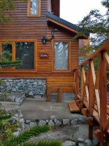 a log cabin with a wooden staircase leading to the entrance at Parajes del Lejano Sur Cabaña El Calden in Moquehue