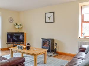 a living room with a table and a fireplace at Old Mill Cottage in Blair Atholl