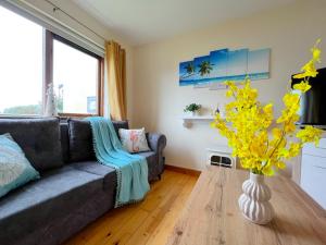 a living room with a couch and a vase with yellow flowers at Summer Breeze - Cosy & Warm Holiday Home in Youghal's heart - Family Friendly - Long Term Price Cuts in Youghal