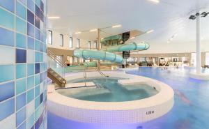 a large swimming pool with a slide in a building at StayAtSea in Katwijk aan Zee