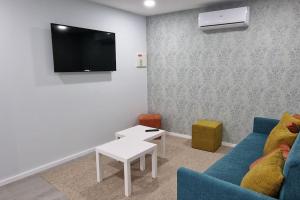 uma sala de estar com um sofá azul e uma televisão em Casa de Férias_As Oliveiras III em Espinho