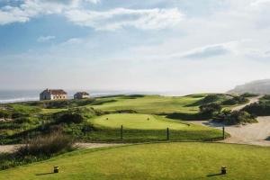 a golf course at the ocean with a house in the background at Casa de Férias_As Oliveiras III in Espinho
