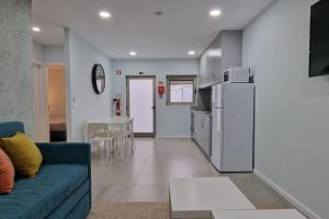 uma sala de estar com um sofá azul e uma cozinha em Casa de Férias_As Oliveiras III em Espinho