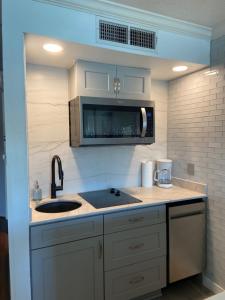 a kitchen with a sink and a microwave at The Victorian Condo/Hotel in Galveston