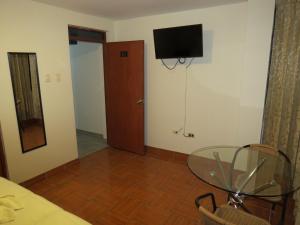 Hospedaje El Rinconcito في جاويا: غرفة مع طاولة زجاجية وتلفزيون على الحائط
