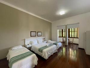 Habitación de hotel con 2 camas y 2 mesas en Pousada Casa Imperatriz - Rua Teresa, en Petrópolis