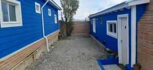 una casa azul junto a un edificio con puerta en Cabañas WerMa en El Calafate