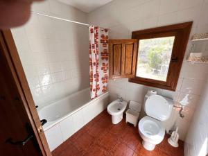 a bathroom with a toilet and a tub and a window at EL RINCON DE YEGEN in Yegen