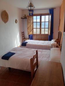 um quarto com três camas e uma mesa e uma janela em EL RINCON DE YEGEN em Yegen