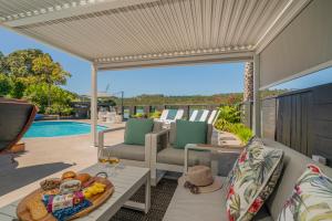 un patio con mesa, sillas y piscina en Oceans 88 Whitianga Coastal Suites, en Whitianga