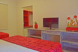 a living room with a television and a bed at Pousada Mais Bella in Ilhabela