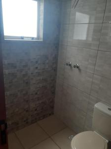 a bathroom with a shower with a toilet and a window at Pousada Nascer da Lua in São Thomé das Letras