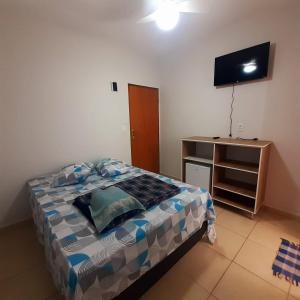 a bedroom with a bed and a tv on the wall at Pousada Nascer da Lua in São Thomé das Letras