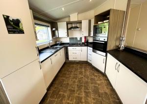 a kitchen with white cabinets and black counter tops at Westlands Country Park in Annan